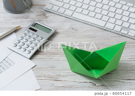 Top view office workspace with green paper ship Top view office workspace with green paper ship 60054117