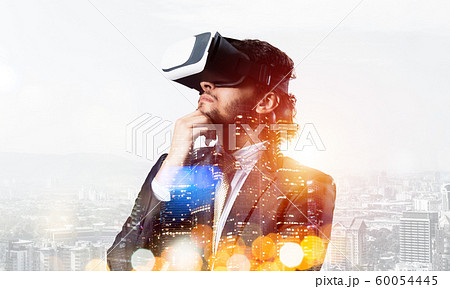 Handsome businessman in bokeh lights experiencing impressive virtual reality technology Handsome businessman in bokeh lights experiencing impressive virtual reality technology 60054445