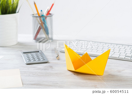 Workspace with office desk and yellow paper ship 60054511