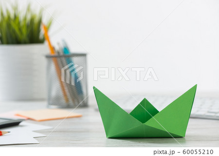 Wooden office desk with green origami boat. Wooden office desk with green origami boat. 60055210