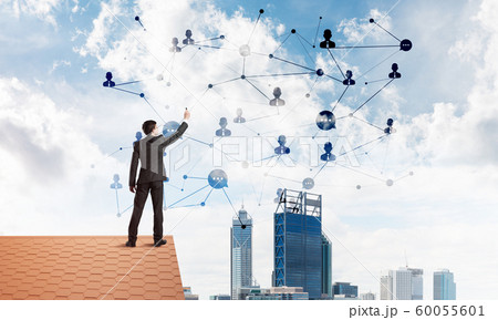 Businessman on house roof presenting networking and connection concept. Mixed media 60055601