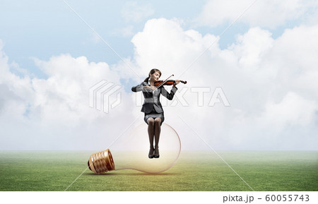 Young woman with violin sitting on glowing lamp Young woman with violin sitting on glowing lamp 60055743