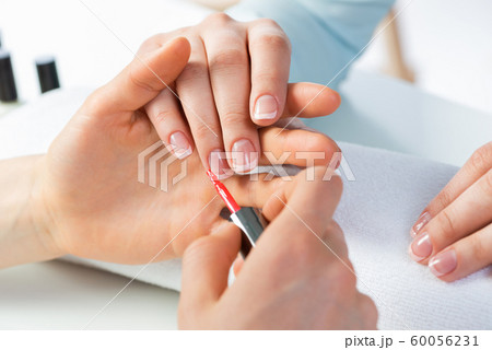 Woman receiving manicure by nail beautician 60056231
