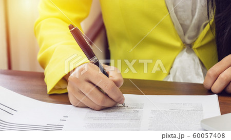 business women in yellow suite use pen sign the signature of consent in the contract agreement document. business partnership and legal agreement of lawyer concept 60057408