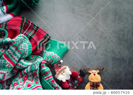 green sweater and red scotch blanket laying on the cement background with a Santa Claus doll and a reindeer for Christmas ornament with copy space green sweater and red scotch blanket laying on the cement background with a Santa Claus doll and a reindeer for Christmas ornament with copy space 60057410