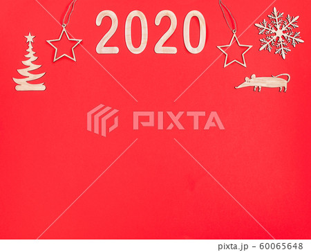 Creative festive Christmas minimal mockup with copy space on red background. Horizontal top border of wooden decorations: numbers 2020, snowflake, Christmas tree, rat and stars. Flat lay, top view. 60065648