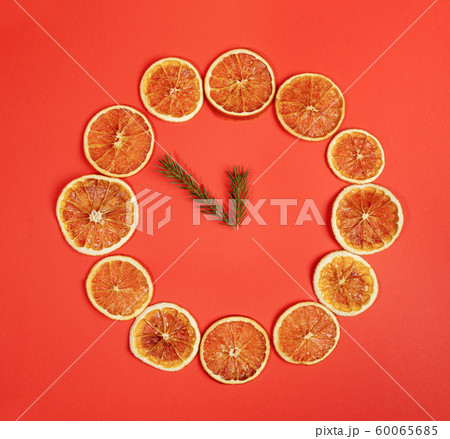 Creative Christmas handmade decor. Dial of watch of dried orange slices with clock hands of fir twigs on red background. Minimal Xmas concept. Top view, flat lay. Square photo. Creative Christmas handmade decor. Dial of watch of dried orange slices with clock hands of fir twigs on red background. Minimal Xmas concept. Top view, flat lay. Square photo. 60065685