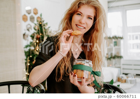 Happy young woman having eating christmas cookies in kitchen Happy young woman having eating christmas cookies in kitchen 60066711