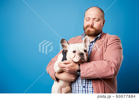 Man with french bulldog in his arms on empty blue background 60077884