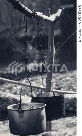 Two sooty old cauldrons on bonfire at forest 60078830