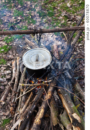 Cooking in old sooty cauldron on campfire at glade 60078870