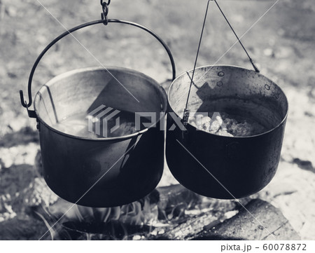 Cooking in two sooty old pots on campfire Cooking in two sooty old pots on campfire 60078872
