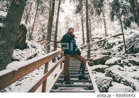 Picture of man in winter forest on wooden bridge . 60080842