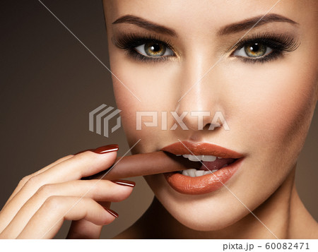 Glamour beautiful woman holds and eats chocolate Glamour beautiful woman holds and eats chocolate 60082471