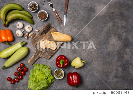 Ingredients for cooking healthy vegetarian food with a board on a dark background. Diet concept. Top view with place for text. 60085448