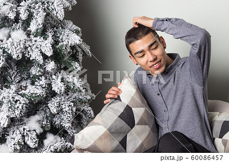 Young happy man sitting on couch near christmas Young happy man sitting on couch near christmas 60086457