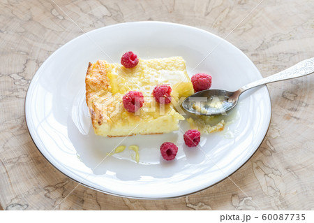 Piece of curd casserole with fresh raspberries and honey on round white plate with spoon on wooden cut. Classic casserole recipe contains: cottage cheese, eggs, sour cream, semolina, butter, sugar. Piece of curd casserole with fresh raspberries and honey on round white plate with spoon on wooden cut. Classic casserole recipe contains: cottage cheese, eggs, sour cream, semolina, butter, sugar. 60087735