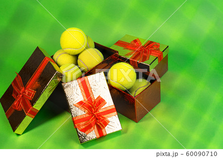 Tennis balls in holiday gift red boxes as present for Christmas, New Year, birthday on green color Tennis balls in holiday gift red boxes as present for Christmas, New Year, birthday on green color 60090710