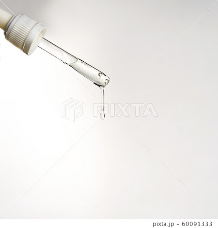 Pipette with drop of serum or hyaluronic acid on gray background. 60091333