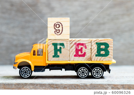 Truck hold letter block in word 9feb on wood background 60096326