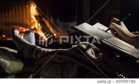 A man begins to write on a blank page of a notebook, sits by the fireplace A man begins to write on a blank page of a notebook, sits by the fireplace 60099780