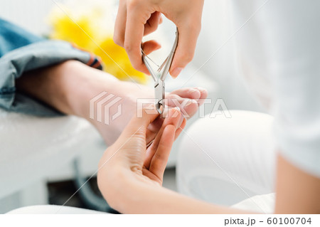 Podiatrist cutting nails on feet of man during pedicure 60100704