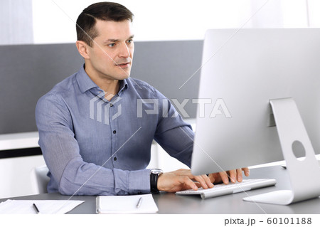 Businessman working with computer in modern office. Headshot of male entrepreneur or company director at workplace. Business concept Businessman working with computer in modern office. Headshot of male entrepreneur or company director at workplace. Business concept 60101188