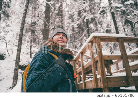 Photo of man in winter forest on wooden bridge. 60101786