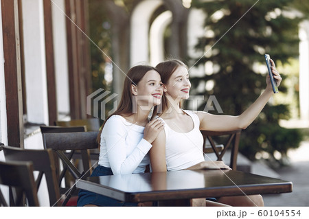 Two elegant and stylish girls in a summer cafe Two elegant and stylish girls in a summer cafe 60104554