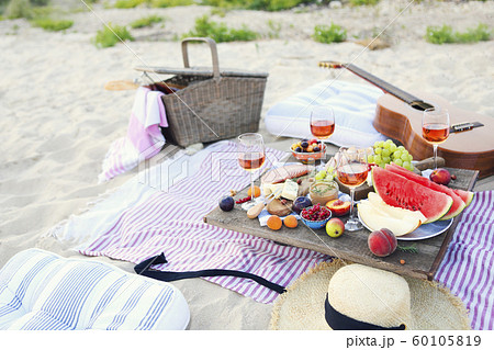 Picnic on the beach at sunset in the style of boho 60105819
