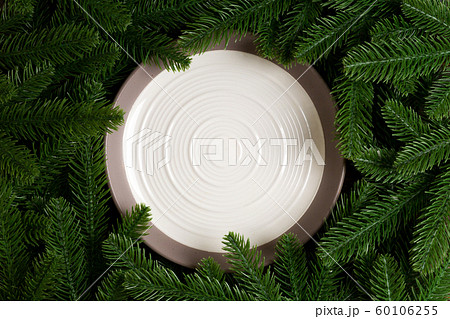 Top view of white plate surrounded with fir tree Top view of white plate surrounded with fir tree 60106255