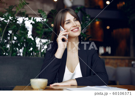 Businesswoman sitting at the table in a cafe and working 60106371