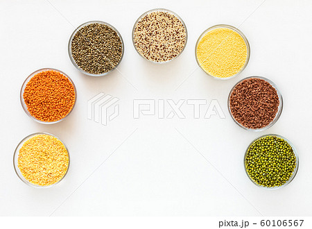 Flat lay glass bowls with cereals, beans and seeds are standing as arc on white background with copy space in middle. Superfood. Healthy food.    60106567