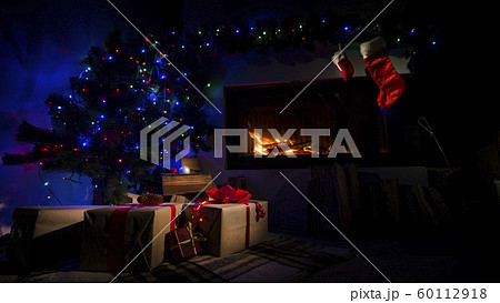 Room in the twilight with a fireplace and a Christmas tree with Christmas presents Room in the twilight with a fireplace and a Christmas tree with Christmas presents 60112918