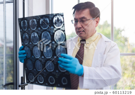 Senior male doctor looking x-ray exam. Senior male doctor looking x-ray exam. 60113219