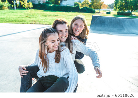 Three girls schoolgirls teenagers 13-15 years old, autumn day summer city, skateboarding relaxing after school on vacation. Emotions joy are fun enjoyment, happy are smiling laughing, casual clothes Three girls schoolgirls teenagers 13-15 years old, autumn day summer city, skateboarding relaxing after school on vacation. Emotions joy are fun enjoyment, happy are smiling laughing, casual clothes 60118626