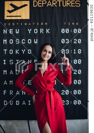 Happy woman in red dress and flight timetable. Happy woman in red dress and flight timetable. 60119630
