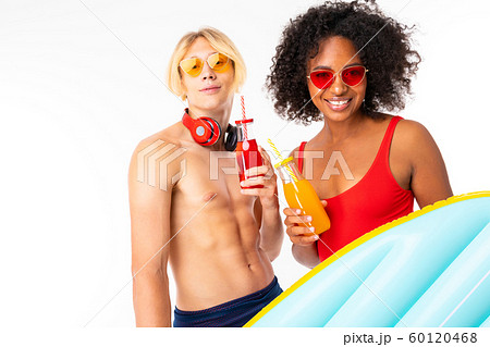 Pretty african female and caucasian blonde man stands in swimsuit with rubber beach mattresses 60120468