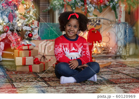 Portrait of little black girl sitting in room decorated for Christmas Portrait of little black girl sitting in room decorated for Christmas 60120969