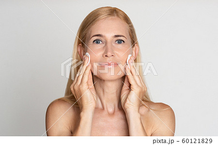 Middle-aged woman removing make up with cotton pads Middle-aged woman removing make up with cotton pads 60121829