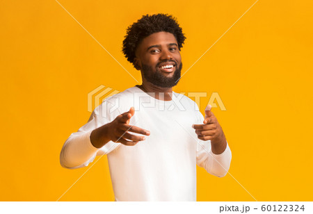 Cheerful black man greeting happily, indicating to camera 60122324