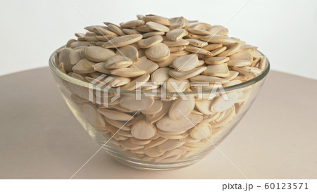 Nuts unpeeled pumpkin seed rotate are on a table in a plate. Snack in transparent dish on an isolated white background are spinning moving. Nuts unpeeled pumpkin seed rotate are on a table in a plate. Snack in transparent dish on an isolated white background are spinning moving. 60123571
