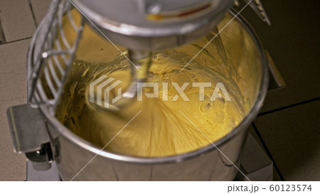 Mixing dough for bread baking with professional kneader spiral machine at the manufacturing. The dough is kneaded for burgers. 60123574