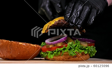 Craft burger is cooking on black background. Consist: sauce, lettuce, tomato, red onion, pickle, cheese, bacon, air bun and marbled meat beef. Craft burger is cooking on black background. Consist: sauce, lettuce, tomato, red onion, pickle, cheese, bacon, air bun and marbled meat beef. 60125096