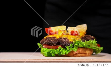 Craft burger is cooking. Consist: red sauce salsa, lettuce, red onion, pickle, cheese, chilli green pepper, air bun and marbled meat beef. 60125177