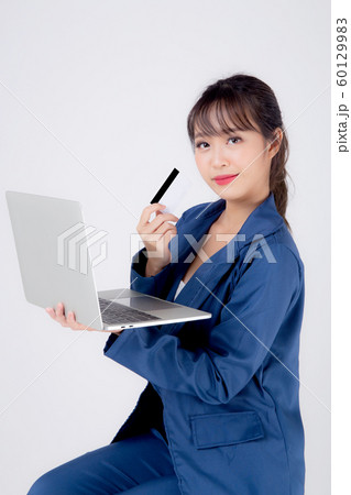 Beautiful young asian business woman happy holding credit card and laptop computer Beautiful young asian business woman happy holding credit card and laptop computer 60129983