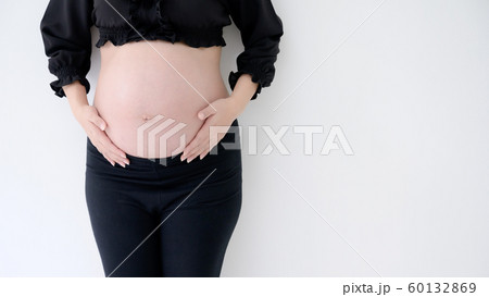 Pregnant woman in black dress and hands hold on belly on a white wall background Pregnant woman in black dress and hands hold on belly on a white wall background 60132869
