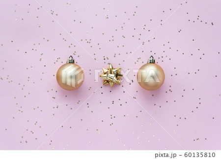 Golden christmas balls, golden bows and star confetti on pink pastel background top view. Flat lay 60135810