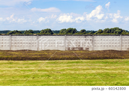 Green grass and industrial concrete fence 60142800