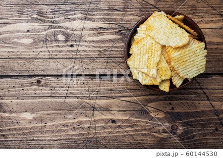 Potato fluted chips with spices in a wooden bowl on a wooden table. copy space. 60144530
